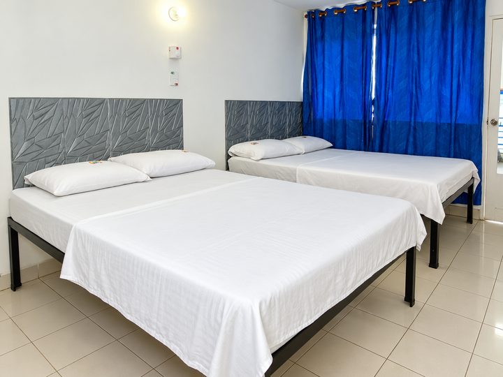 Habitación con dos camas dobles y cortinas azules