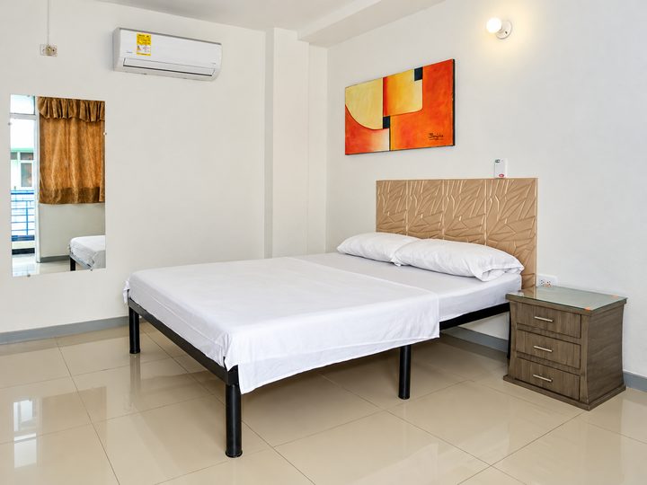 Habitación con cama doble, cabecero tapizado, cuadro naranja y aire acondicionado