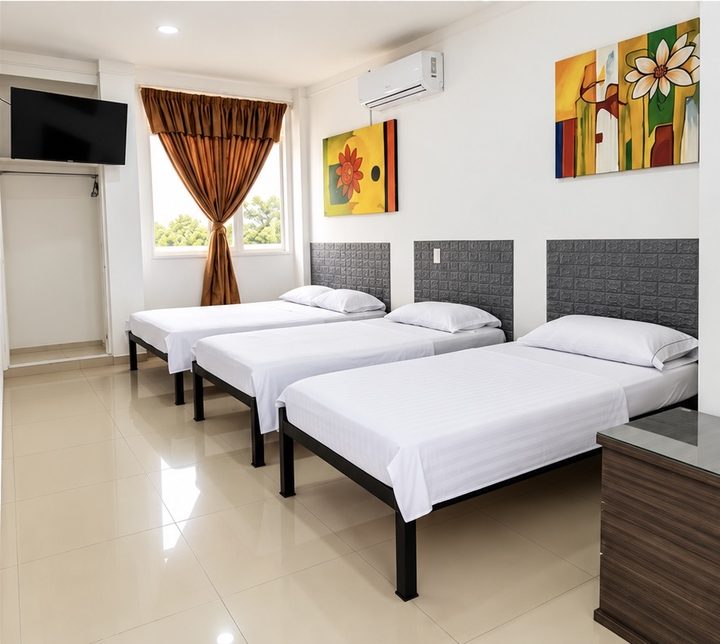 Habitación con una cama doble y dos sencillas, aire acondicionado y televisor