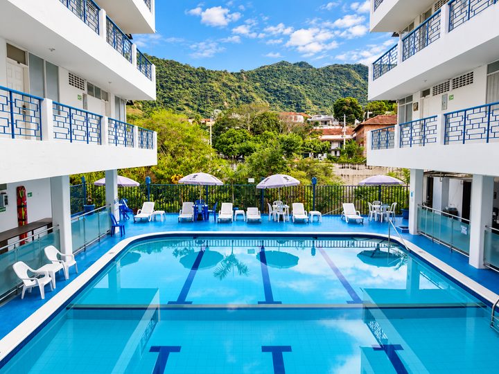 Piscina con sombrillas y asoleadoras, con la montaña al fondo